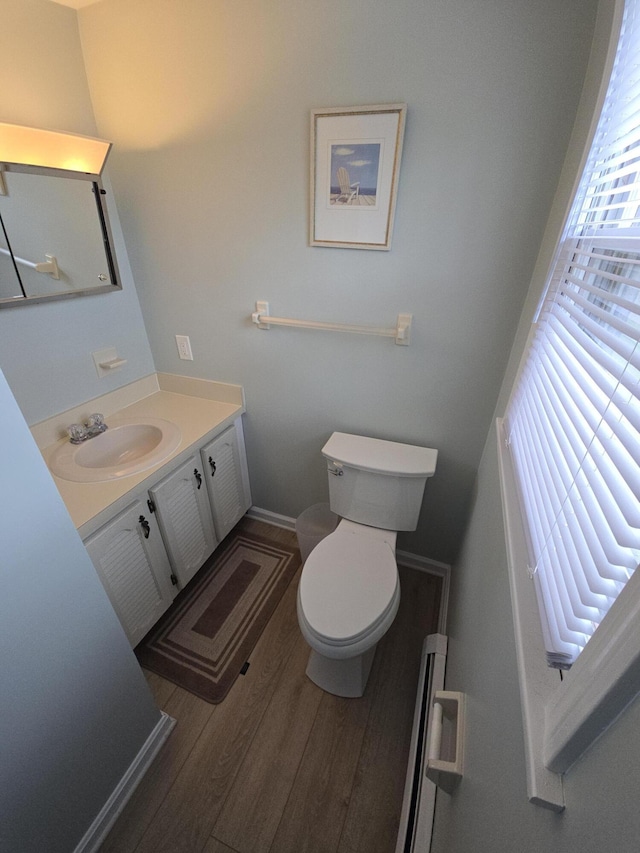 bathroom featuring toilet, baseboards, wood finished floors, and vanity