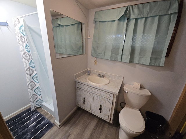 bathroom with a stall shower, wood finished floors, vanity, baseboards, and toilet