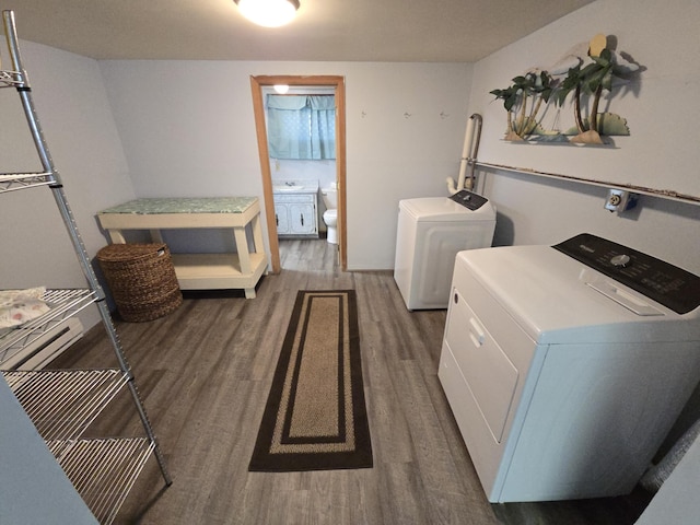 clothes washing area with washing machine and clothes dryer, laundry area, and wood finished floors