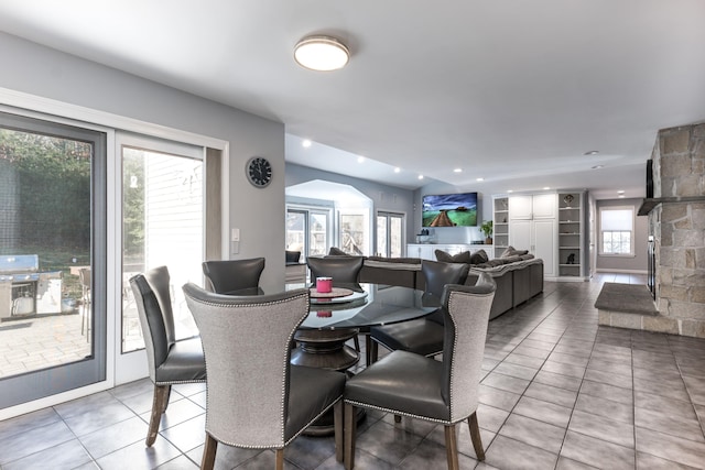 tiled dining area featuring plenty of natural light and a fireplace