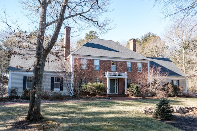 colonial home featuring a balcony and a front yard