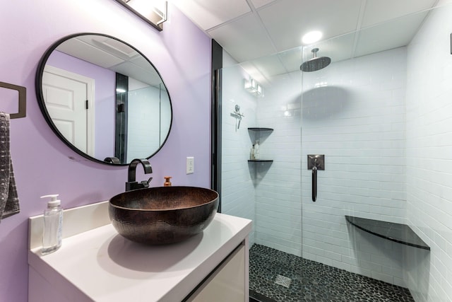 bathroom with tiled shower and vanity