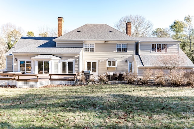 rear view of property featuring a lawn and a deck