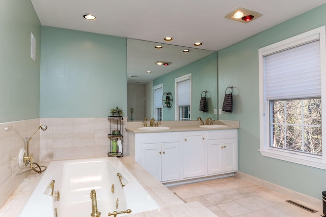 bathroom featuring tile patterned flooring, tiled tub, and vanity