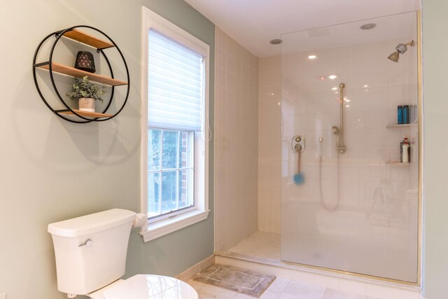 bathroom featuring a tile shower, plenty of natural light, and toilet