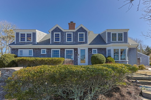 shingle-style home featuring roof with shingles and a chimney