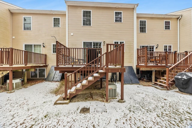 snow covered rear of property featuring central air condition unit and a wooden deck