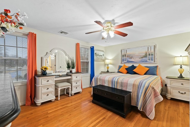 bedroom with ceiling fan, light wood-style flooring, visible vents, and baseboards