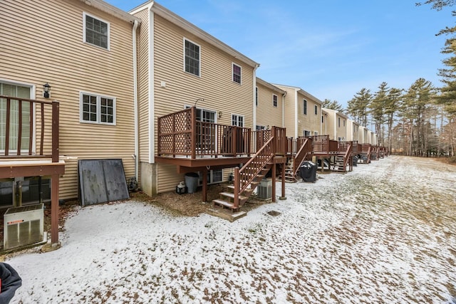 snow covered back of property featuring central AC, stairway, and a wooden deck