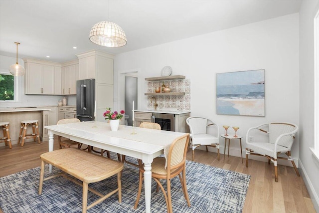 dining area with wine cooler and light wood-type flooring