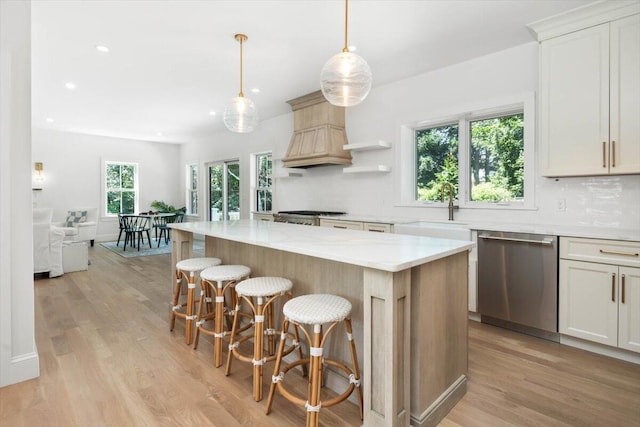 kitchen featuring a center island, white cabinetry, decorative backsplash, stainless steel dishwasher, and sink