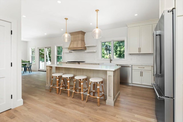 kitchen with appliances with stainless steel finishes, a kitchen island, decorative light fixtures, decorative backsplash, and a kitchen breakfast bar