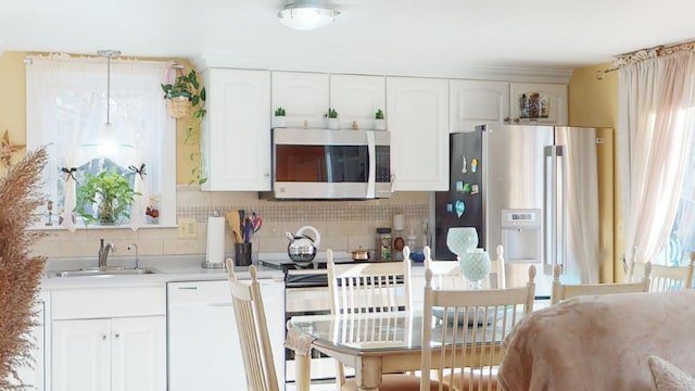 kitchen featuring appliances with stainless steel finishes, decorative backsplash, white cabinets, decorative light fixtures, and sink