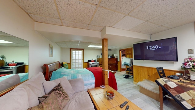 living room featuring a paneled ceiling and wood walls