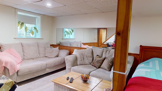 living room featuring a drop ceiling and wooden walls