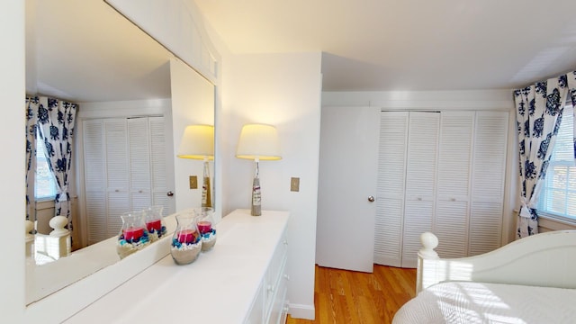 bedroom with multiple closets and light hardwood / wood-style floors