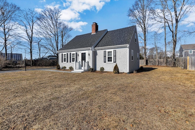 view of front of house featuring roof with shingles, a chimney, fence, and a front yard