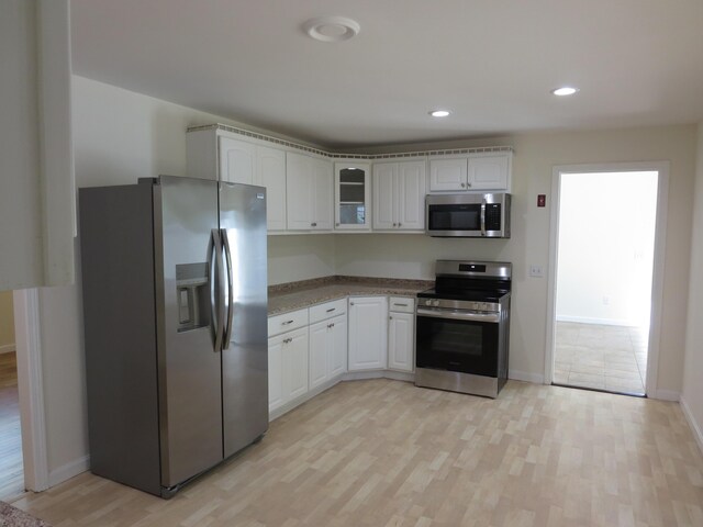 130 Fuller Rd, Centerville, MA 02632 - kitchen with stainless steel appliances, light wood-style floors, white cabinets, glass insert cabinets, and baseboards
