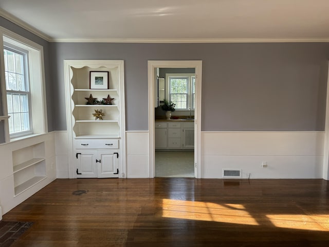 spare room with dark hardwood / wood-style flooring, sink, built in features, and crown molding