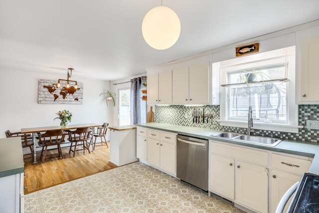 kitchen with stainless steel dishwasher, white cabinetry, a sink, decorative light fixtures, and backsplash