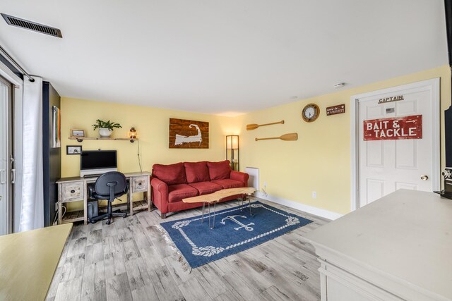living area featuring baseboards, visible vents, and wood finished floors