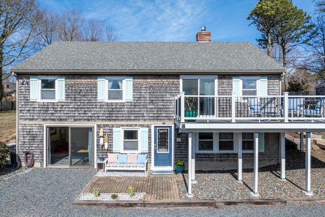 view of front of home featuring a shingled roof, a patio area, and a chimney