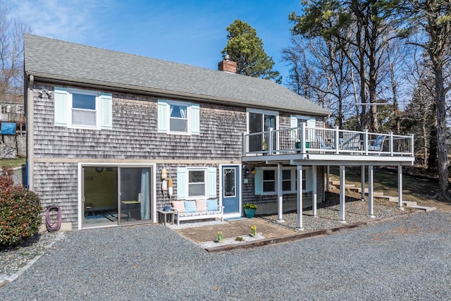 view of front of property with a chimney, a shingled roof, and a wooden deck