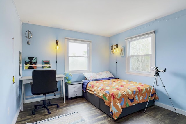 bedroom with multiple windows, wood finished floors, and baseboards