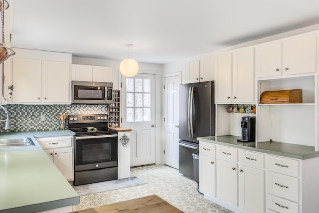 kitchen with decorative backsplash, stainless steel appliances, white cabinetry, a sink, and pendant lighting
