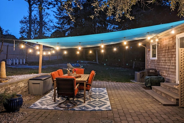 patio at night featuring outdoor dining space and grilling area
