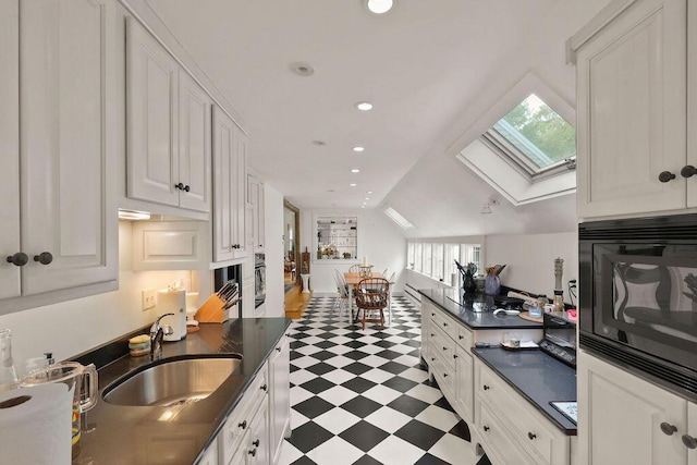 181 Pleasant St, South Yarmouth, MA 02664 - kitchen with black appliances, light floors, a sink, dark countertops, and a skylight