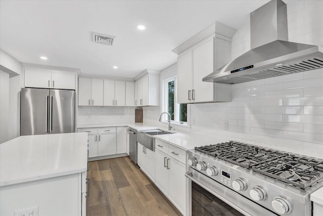 kitchen featuring wall chimney exhaust hood, sink, white cabinetry, dark hardwood / wood-style flooring, and stainless steel appliances