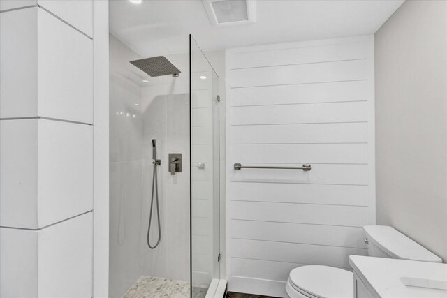 bathroom with a tile shower, vanity, and toilet