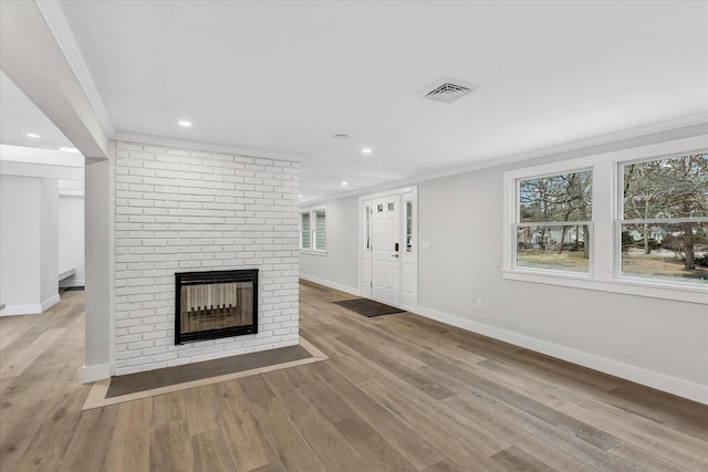 unfurnished living room featuring crown molding, a fireplace, and light wood-type flooring