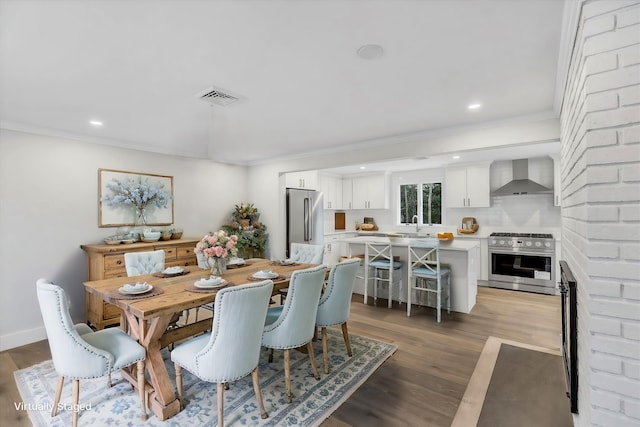 dining space with ornamental molding, sink, and hardwood / wood-style floors