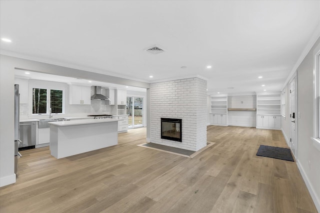 unfurnished living room with ornamental molding, sink, a brick fireplace, and light wood-type flooring