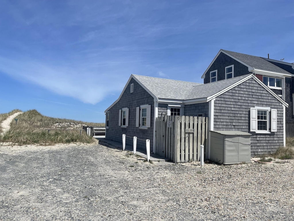 view of side of home with fence and a shingled roof