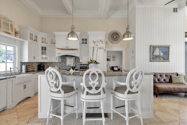 16 Beach View Rd, West Dennis, MA 02670 - kitchen with a sink, decorative backsplash, white cabinets, a kitchen bar, and ornamental molding