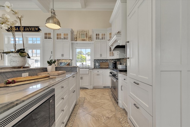 16 Beach View Rd, West Dennis, MA 02670 - kitchen featuring high end stove, built in microwave, backsplash, white cabinetry, and ornamental molding