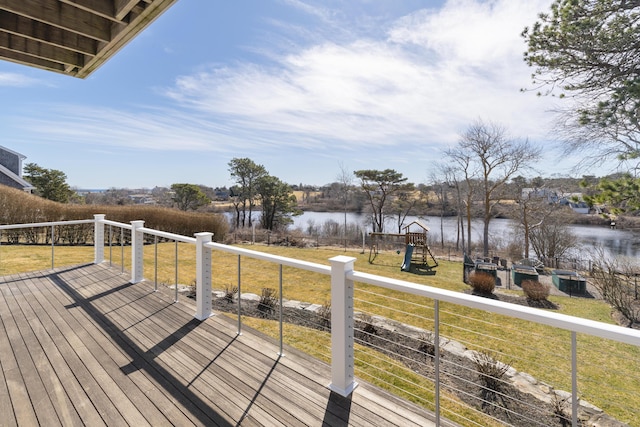 wooden terrace featuring a water view, a lawn, and a playground