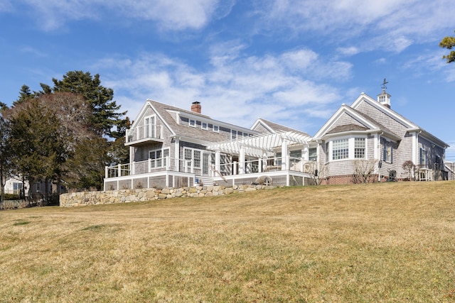 rear view of property featuring a yard, a pergola, and a chimney