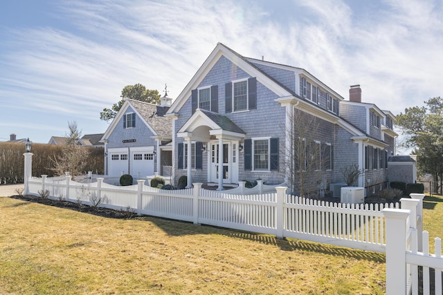 shingle-style home with a fenced front yard, a chimney, and a front lawn