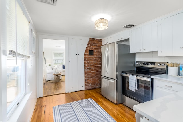 429 Paines Creek Rd, Brewster, MA 02631 - kitchen featuring appliances with stainless steel finishes, brick wall, light wood finished floors, white cabinets, and light countertops
