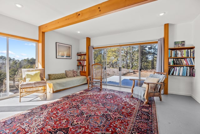 living room with beamed ceiling, plenty of natural light, and concrete flooring