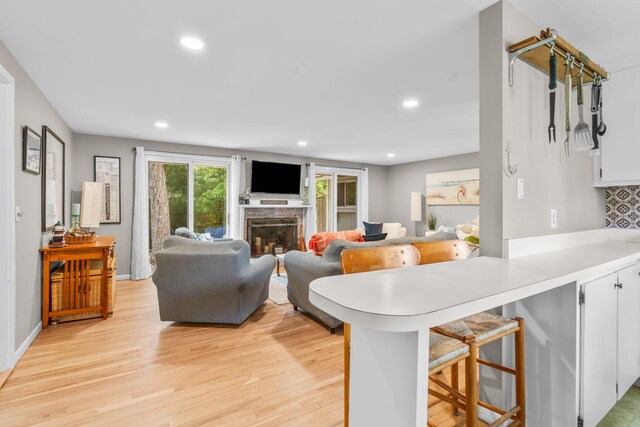 12 Running Light Way, Mashpee, MA 02649 - kitchen with light wood-style floors, light countertops, a fireplace, a breakfast bar, and a peninsula
