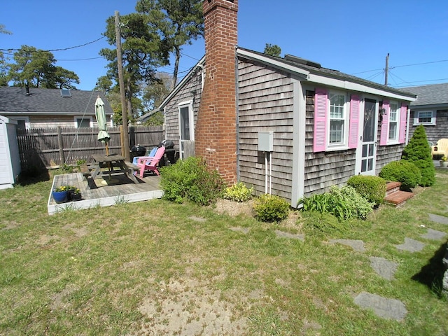 view of property exterior with a chimney, fence, a patio area, and a lawn