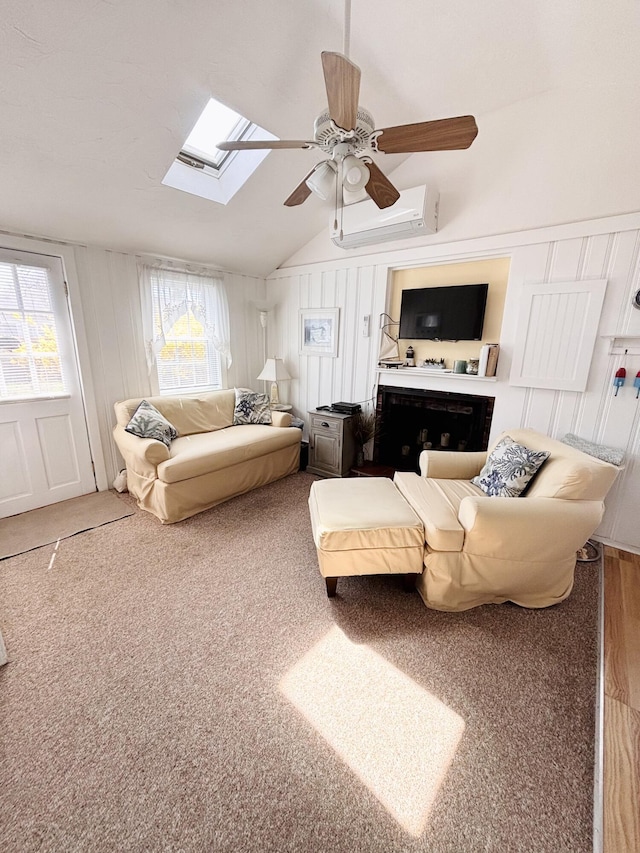 living area featuring vaulted ceiling with skylight, a ceiling fan, a fireplace, a decorative wall, and a wall mounted air conditioner