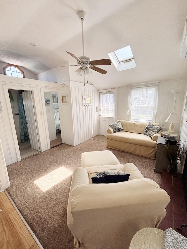 living area with ceiling fan, plenty of natural light, and vaulted ceiling with skylight