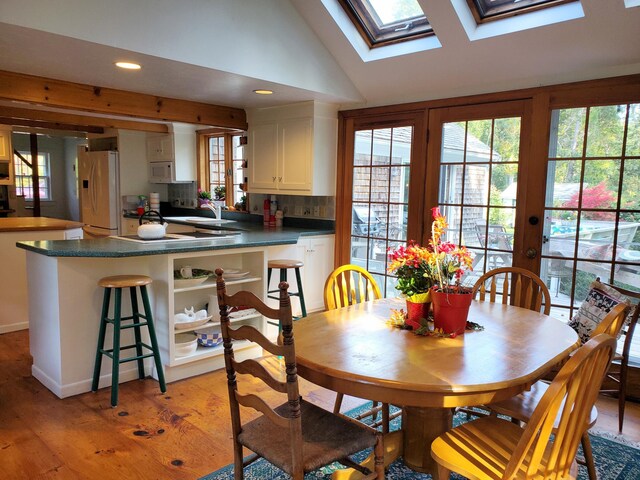 dining room with sink, lofted ceiling with skylight, and light hardwood / wood-style floors