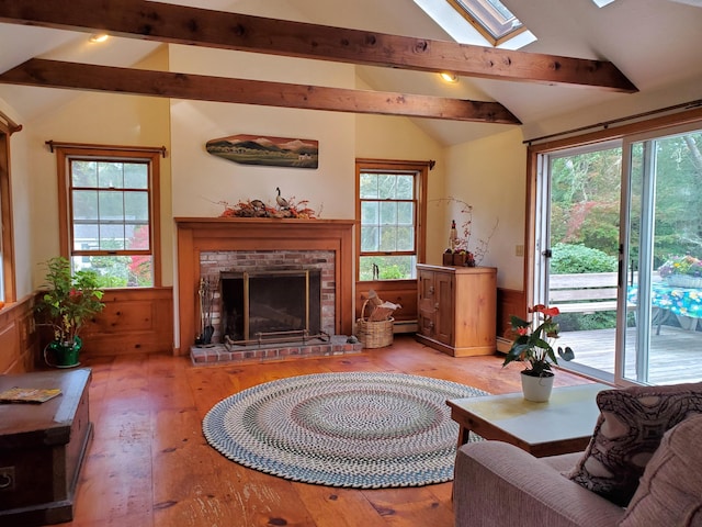 living room with a brick fireplace, lofted ceiling with skylight, and light hardwood / wood-style floors